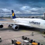 Avion Lufthansa blanc et bleu immobilisé à la porte d'embarquement d'un aéroport