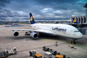 Avion Lufthansa blanc et bleu immobilisé à la porte d'embarquement d'un aéroport