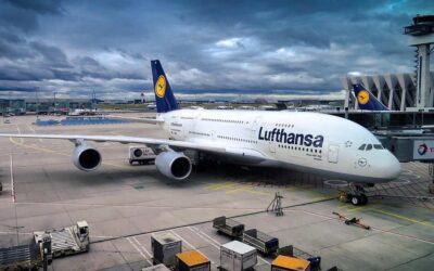 Avion Lufthansa blanc et bleu immobilisé à la porte d'embarquement d'un aéroport