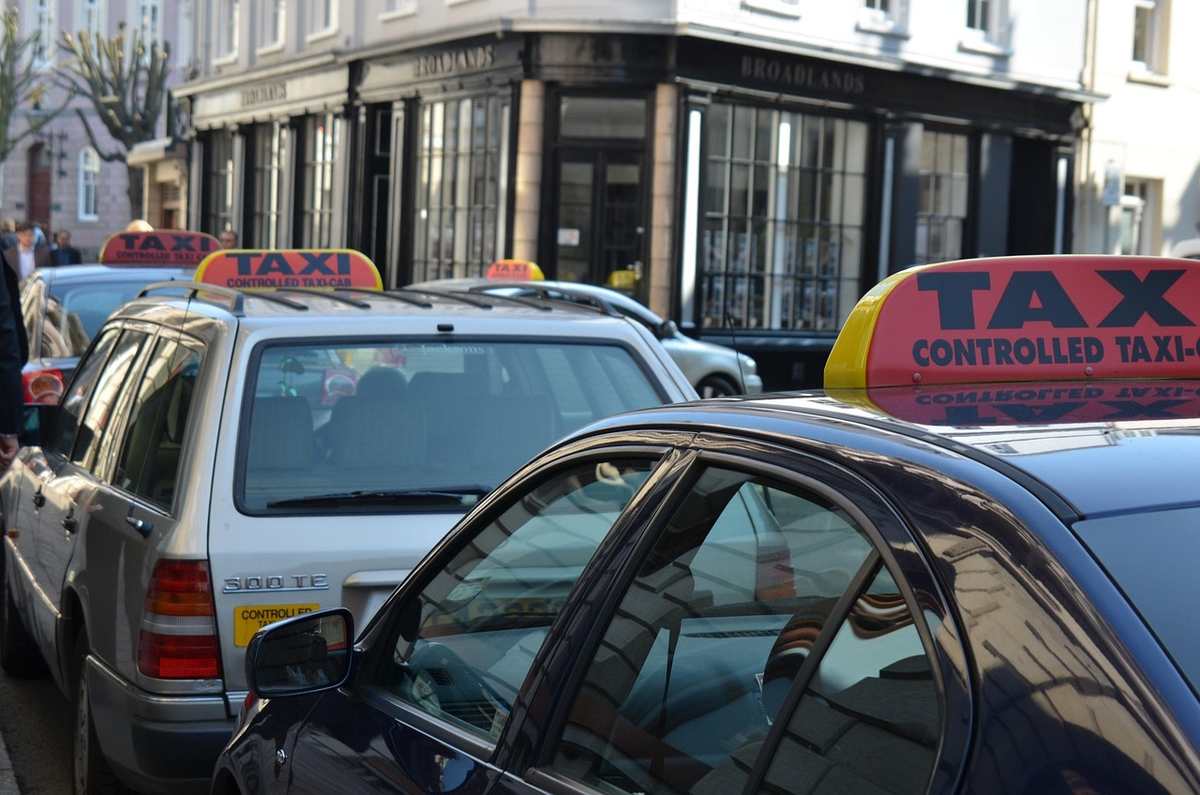 Des taxis et voitures stationnés sur une rue devant un immeuble