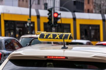 Un taxi jaune avec enseigne sur le toit, vue arrière d'une voiture